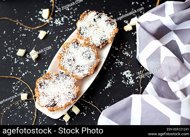 coconut muffins on a black background with candied coconut and gray cloth