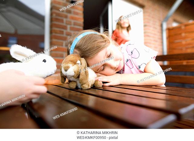 Girl lying on garden table with toy bunny