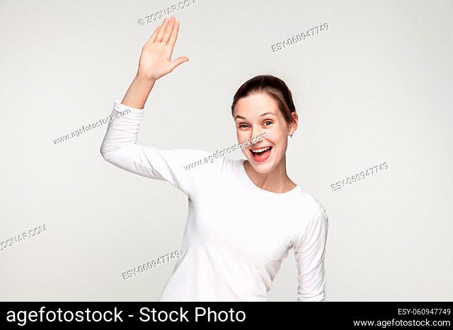 Hi! How are you? Happiness woman showing hello sign. Studio shot, gray background