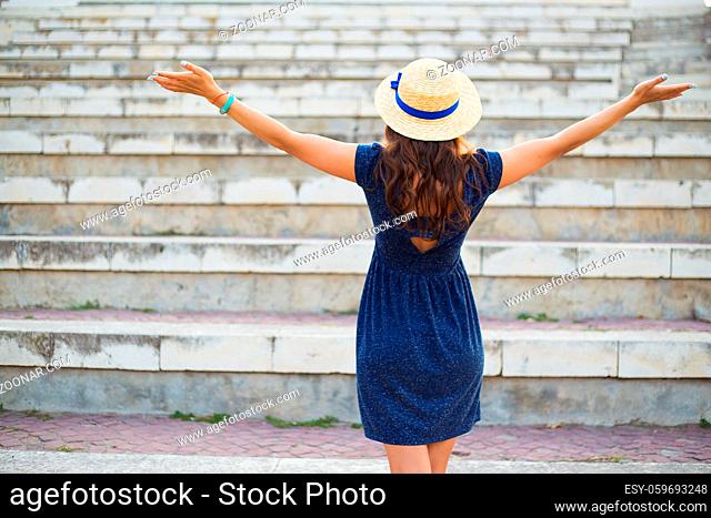 Beautiful girl on the steps in a blue dress and hat