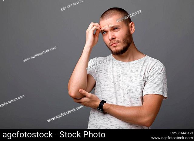 Portrait of frustrated young man on gray background. sadness