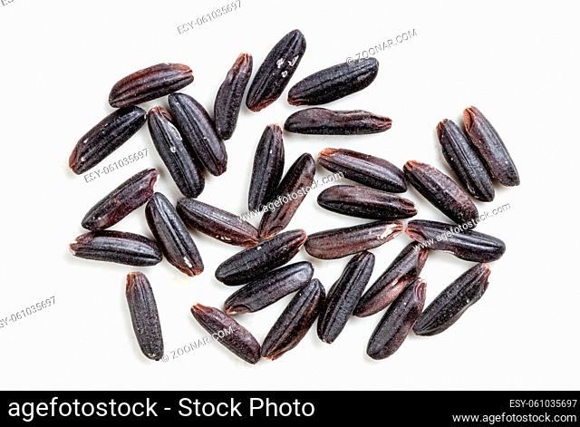 several raw black rice grains close up on gray ceramic plate