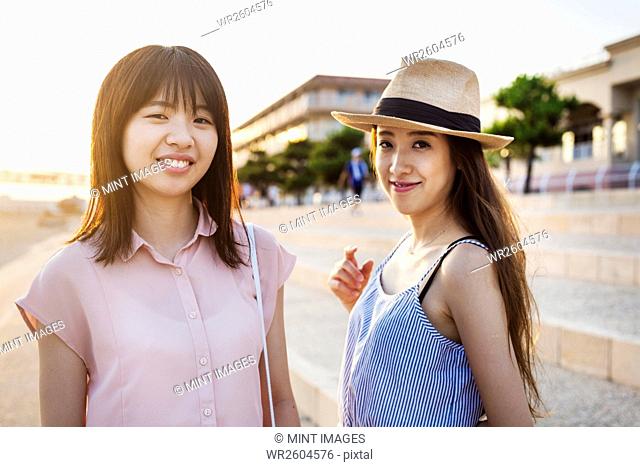 Two young women with long brown hair outside a shopping centre