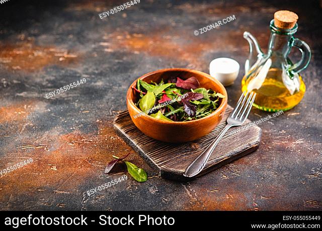 Fresh salad mix of baby spinach, arugula leaves and chard in wooden bowl, healthy food