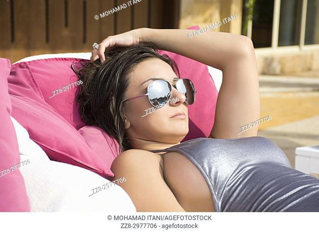 Beautiful woman in bikini sunbathing wearing sunglasses