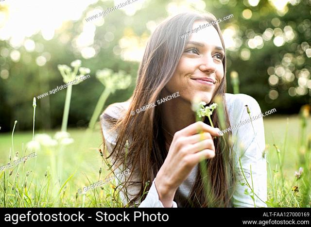 Portrait of smiling young woman lying in park