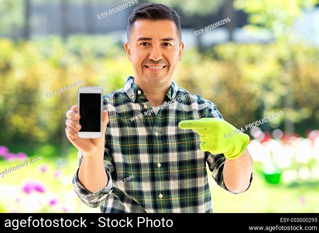 middle-aged man with smartphone at summer garden