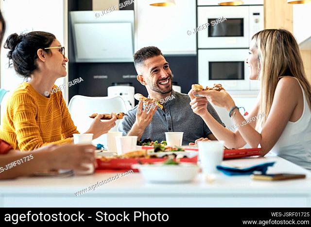 Smiling businessman with pizza talking to businesswoman at office cafeteria
