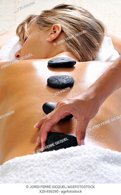 Hand placing hot stone for therapy