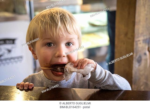 Messy Caucasian boy eating popsicle in kitchen