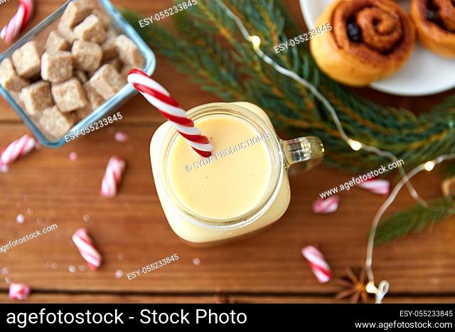 eggnog with candy cane in mug and cinnamon buns