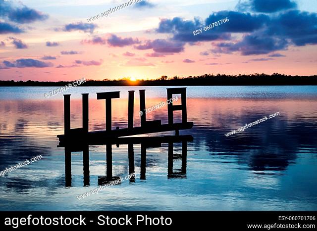 Sun setting at the calm lagoon behind Utila sign, Utila, Honduras, Central America