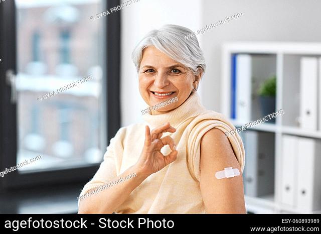 smiling vaccinated woman with medical patch on arm
