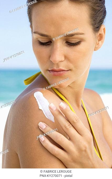 Woman applying suntan lotion on her shoulder