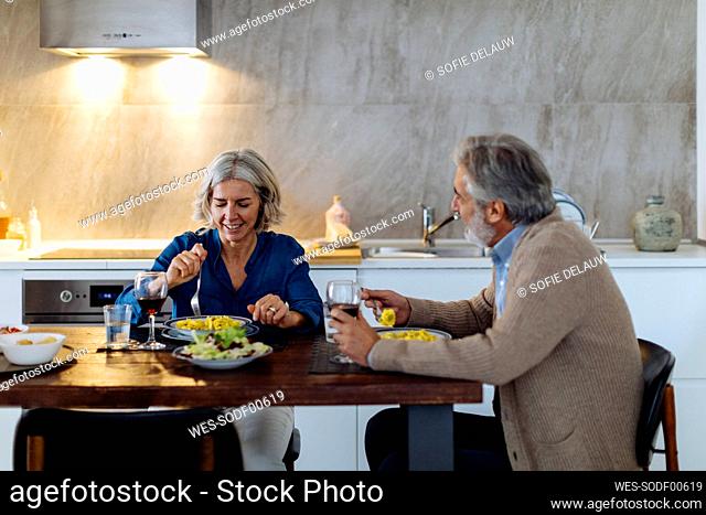 Mature couple having dinner in kitchen at home