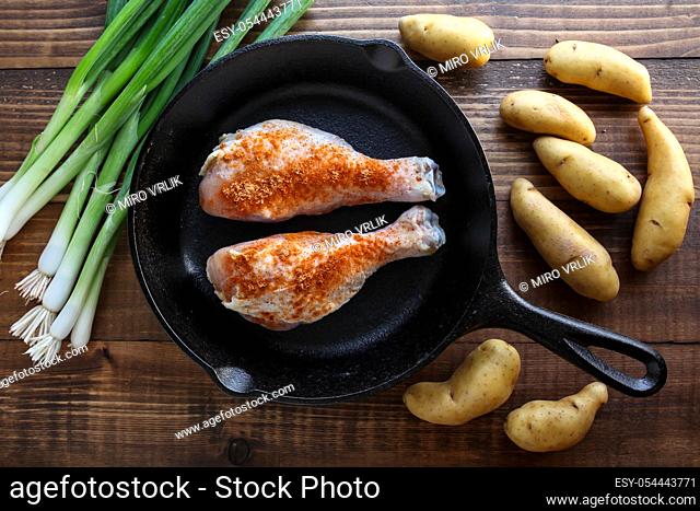 Iron skillet with chicken leggs and ingredients