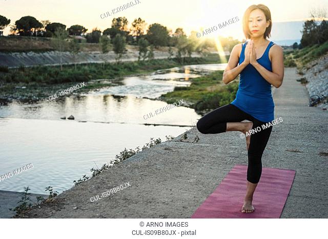 Mature woman in rural setting, standing on one leg in yoga position