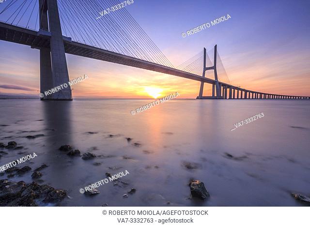 The colors of dawn on Vasco da Gama Bridge that spans the Tagus River in Parque das Nações Lisbon Portugal Europe
