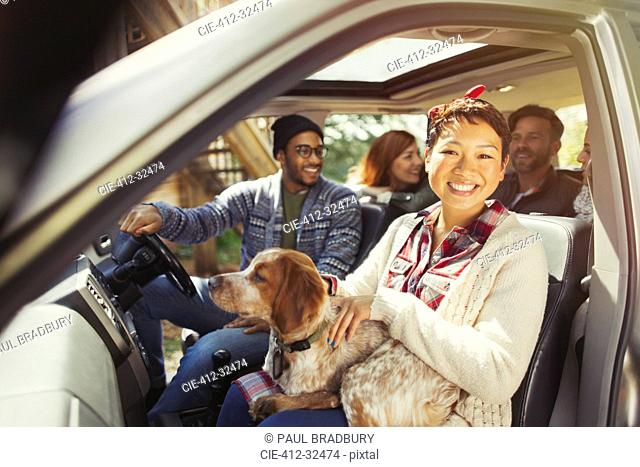 Portrait smiling woman with dog on lap in car with friends