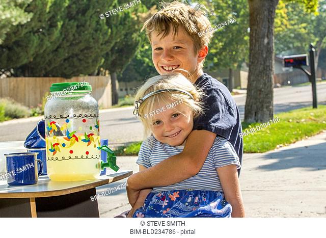 Smiling Caucasian boy hugging girl and selling lemonade
