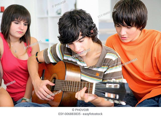 Teens listening to their peer play the guitar