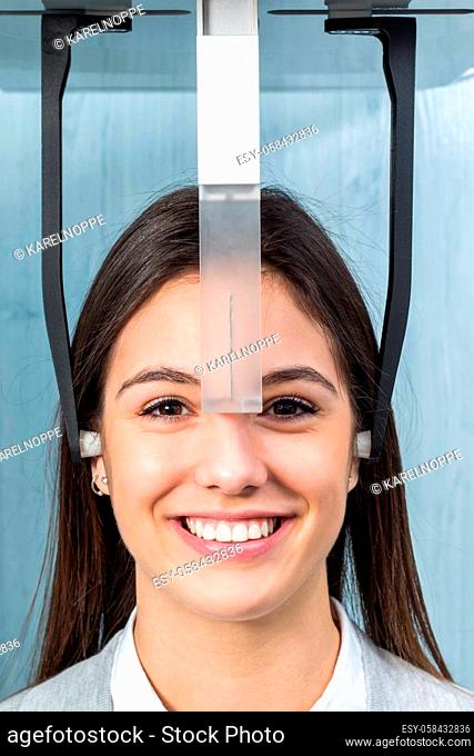 Close up face shot of girl taking dental x-ray on cephalometric panorama machine in clinic