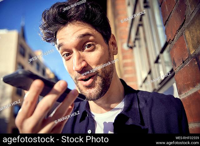 Happy businessman talking on mobile phone while standing outdoors