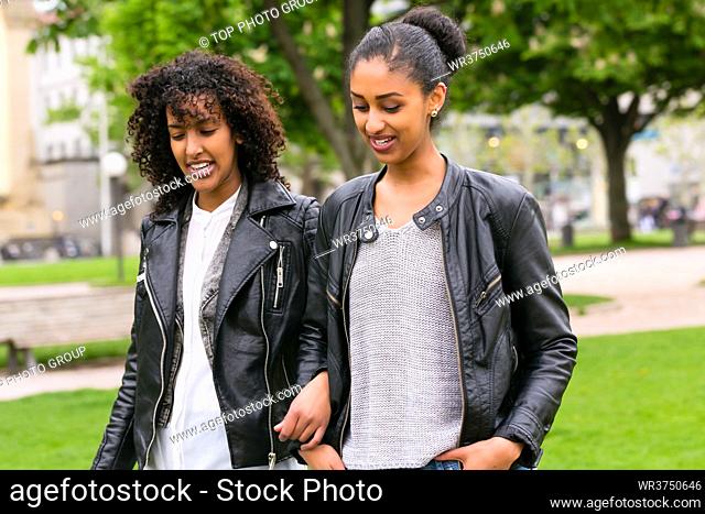 Two north African teen friends take a walk in the park talking