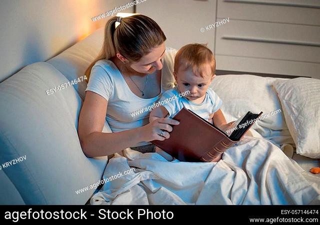Portrait of mother reading book to her baby son before going to sleep