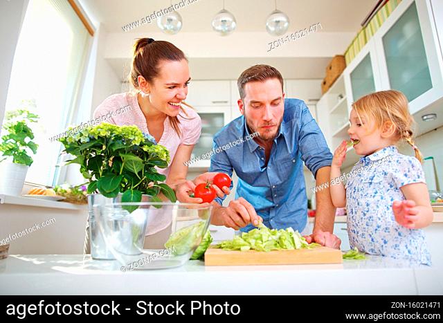 Glückliche Familie gemeinsam in der Küche mit Salat und Tomaten