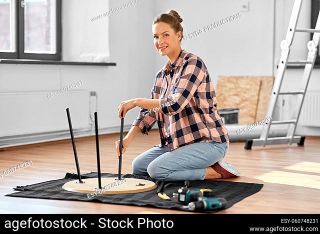 happy woman assembling coffee table at new home