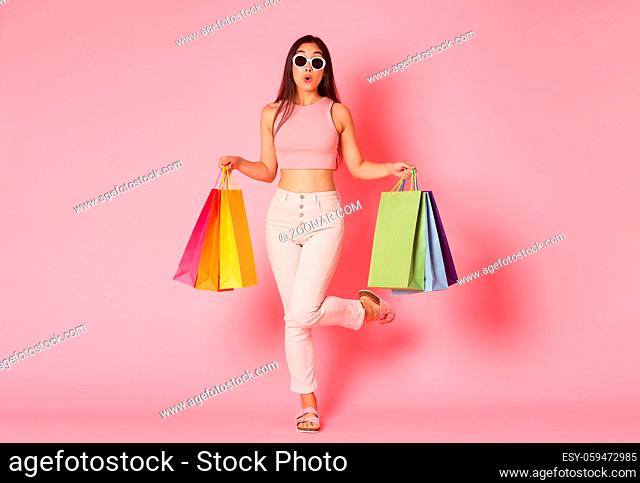 Full length portrait of silly cute asian girl in sunglasses sport awesome sale promo in store, running to shop with curious excited expression