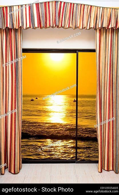 beautiful sunset on the sea view from the window with curtains open