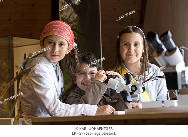 children investigate with a microscope in the Springe Museum, region Hannover, Lower Saxony, northern Germany