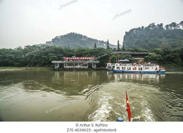 Ferry cruising below Leshan Giant Buddha site on an overcast day. Sichuan Province, People's Republic of China