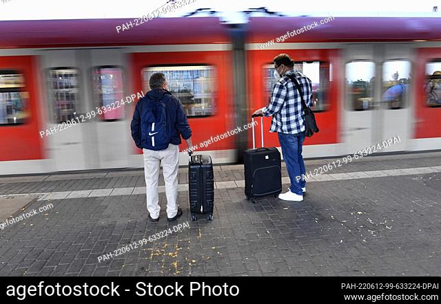12 June 2022, North Rhine-Westphalia, Cologne: Travelers wait for a train at Deutz station early in the morning. On the second weekend with a 9-euro ticket