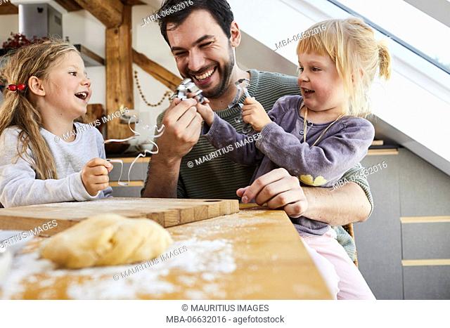 Family baking christmas cookies, father and daughters having fun