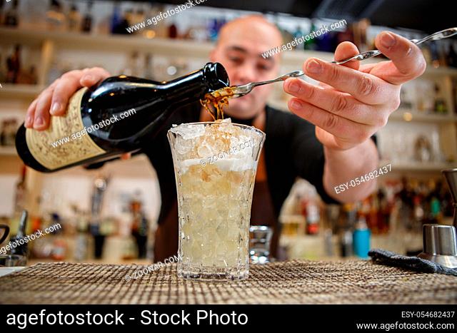 Bartender pouring cocktail into glass at the bar