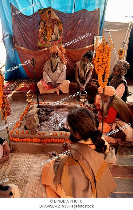 Naga sadhus from the Juna Akadha sits with his Trishul at their camp during the Ardh Kumbh Mela , , , India