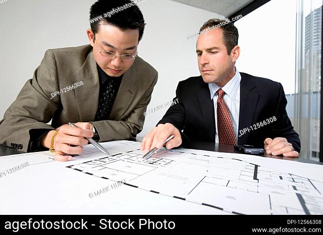 Two architects discussing on blueprints in an office