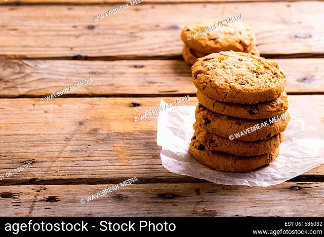 Cookies stacked on parchment paper at wooden table, copy space