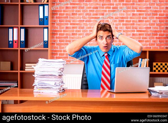 Young employee with excessive work sitting at the office