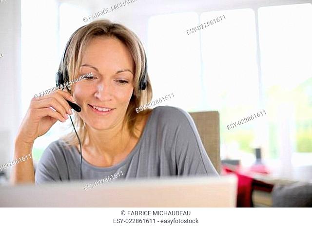 Portrait of woman with headset in front of laptop
