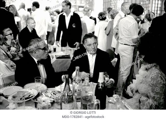 Greek shipowner Aristotele Onassis and British actor Richard Burton (Richard Walter Jenkins) dining during the party in the halls of Ca' Vendramin Calergi...