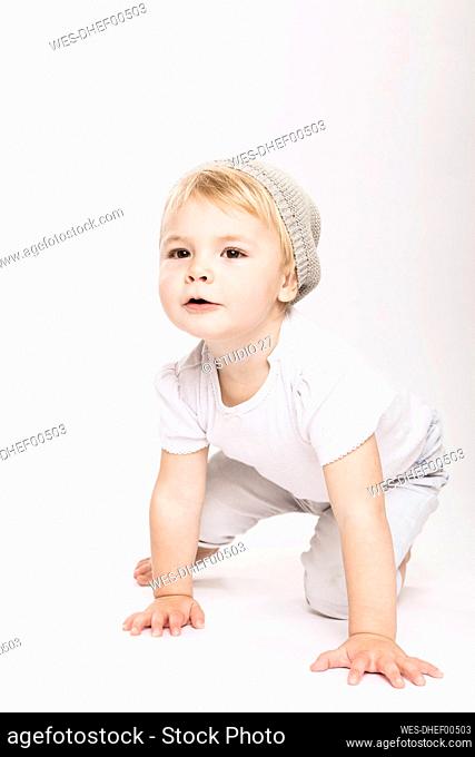 Cute little toddler girl crawling in studio against white background
