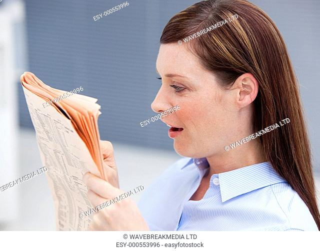 Surprised businesswoman reading newspaper in her office