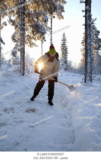 Man shoveling snow on rural path