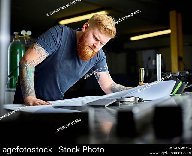 Male professional analyzing business plan while standing at factory