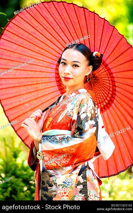 Portrait of woman in kimono holding red parasol