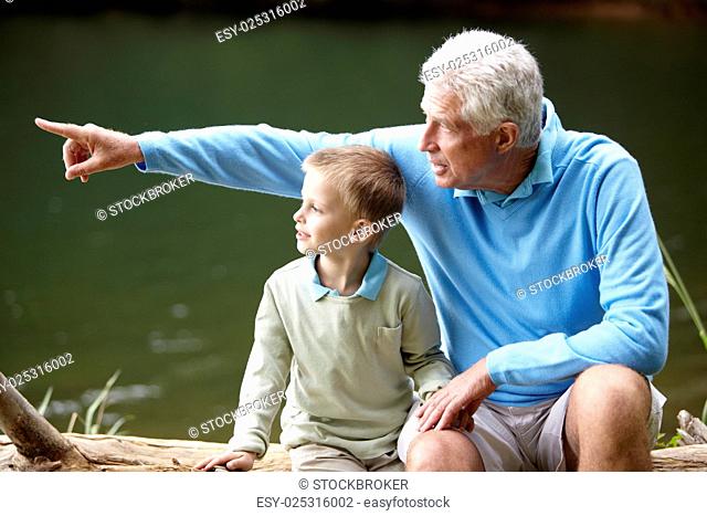 Grandfather and grandson sitting by lake